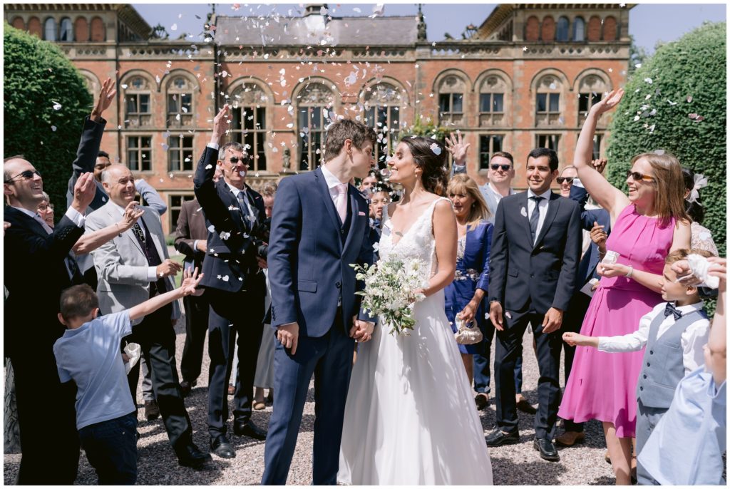 Intimate UK destination wedding ceremony at Exclusive Wedding Venue Soughton Hall , bride and Groom with white rose petal confetti