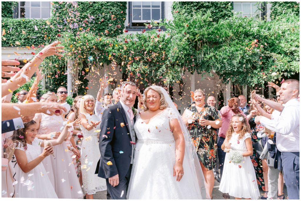 Summer outdoor wedding at Statham Lodge in Lymm, with Bride and Groom showered with bright paper confetti