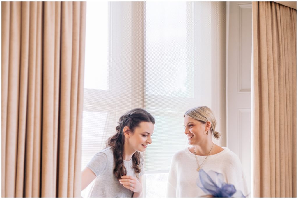Two Bridesmaid relax in the Large bay window of the bridal suite at Hartsfield manor 